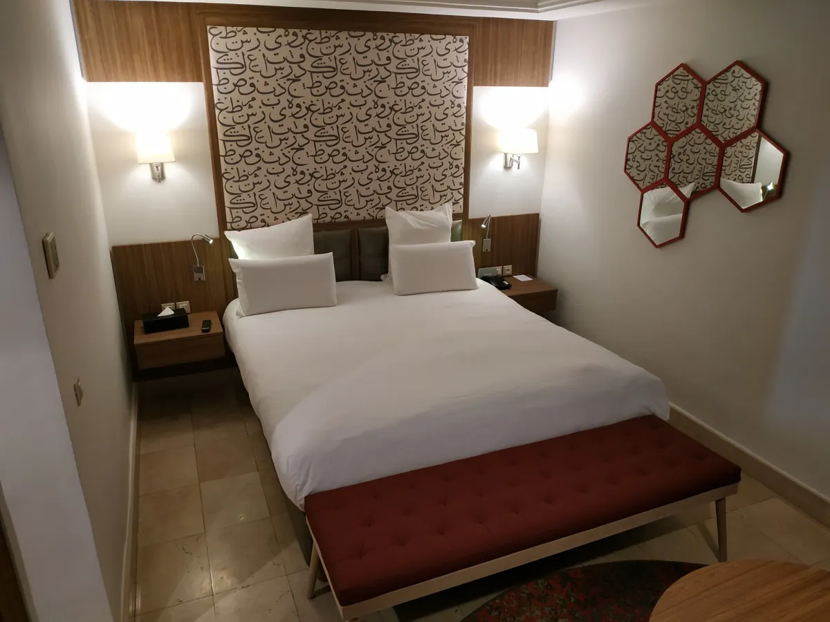 Cama con cabecero de caligrafía y espejos hexagonales en el Barceló Marrakech