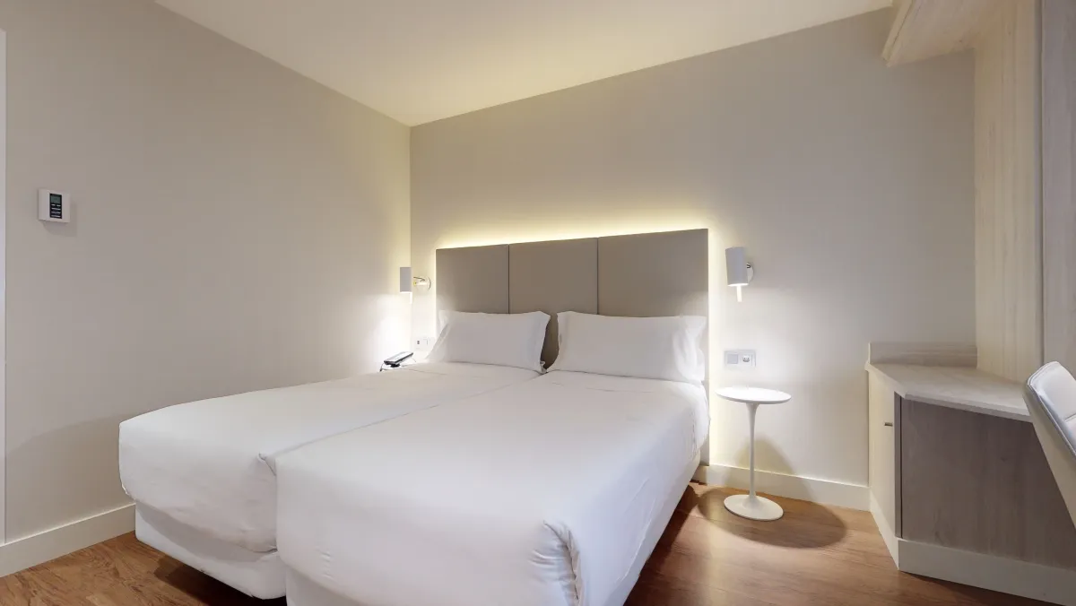 Dos camas con cabecero iluminado en la habitación 304 del NH Madrid Barajas